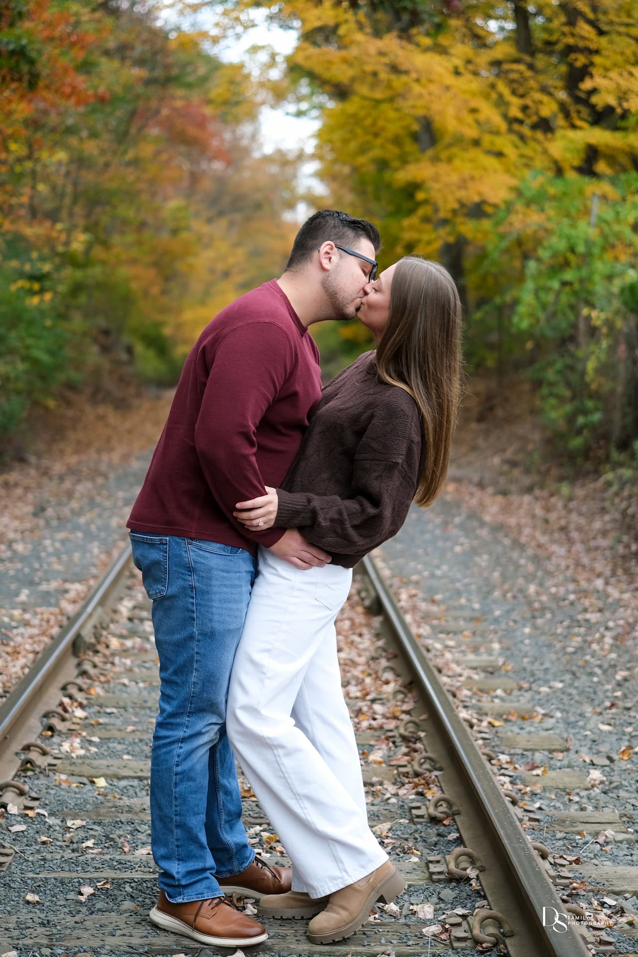 Candid engagement moment among fall leaves